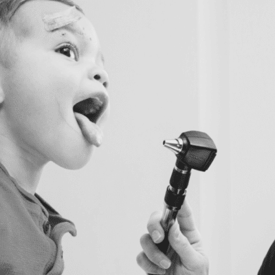 Female doctor examining toddler with otoscope